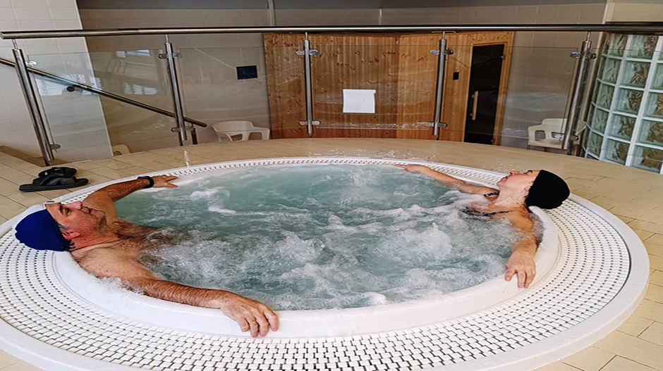 Dos usuarios disfrutando del jacuzzi. Al fondo, la sauna.