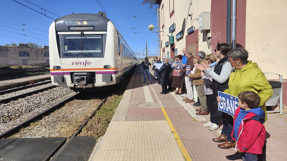 Los vecinos aplauden y muestran los carteles a la llegada del tren.