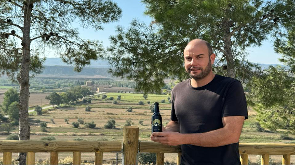 José Jaime Castellón, con la cerveza Sixena. Al fondo, el monasterio de Sijena, al que rinde homenaje.