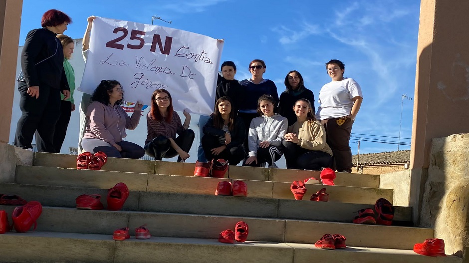 Uno de los grupos de la escuela de adultos exhibiendo los zapatos rojos elaborados en los talleres y una pancarta en conmemoración de este Día Internacional de la Eliminación de la Violencia contra la Mujer.