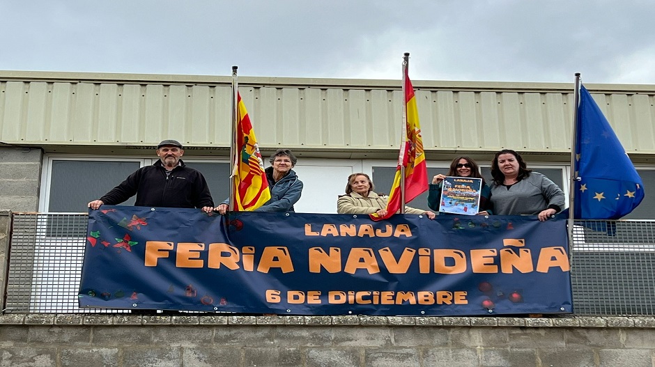 Integrantes de la Asociación La Estiva, junto al cartel de la Feria Navideña celebrada el próximo 6 de diciembre en Lanaja.